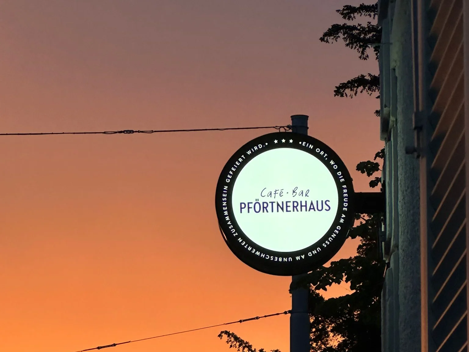 Das Café-Bar-Pförtnerhaus-Schild vor dem Abendhimmel